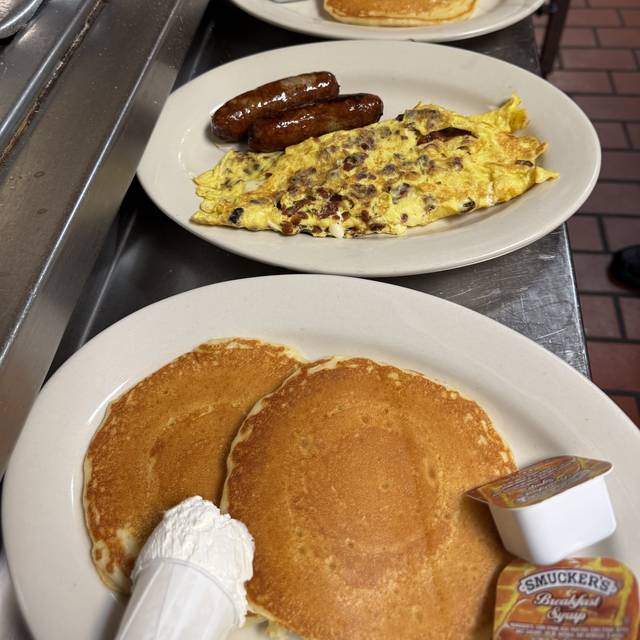 Plates of hot cakes and omelets with sausage lined up on the pass, ready to go out