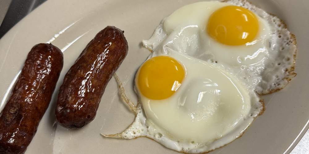 Two sunny-side-up eggs with two sausage links on a diner plate