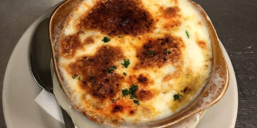 A crock of French onion soup with browned, bubbling cheese on top